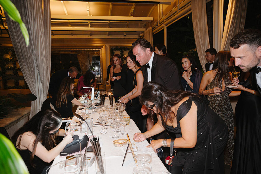 Wedding guests lined up to get their wedding favors personalized by calligraphers